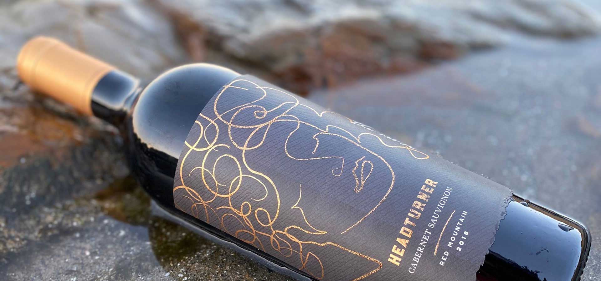 Bottle of Headturner Wine Laying On Its Side Along the Shore